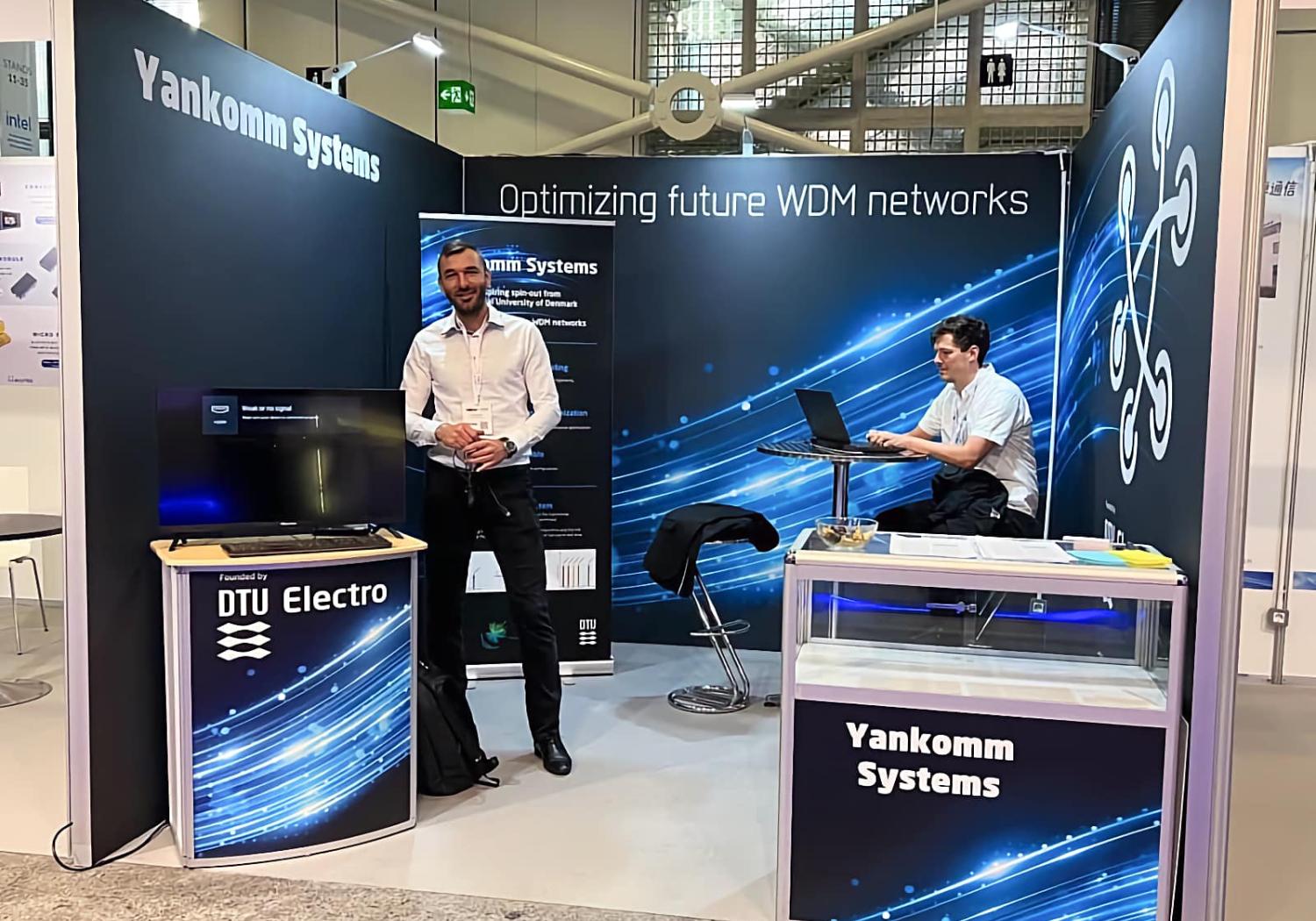 Stand for Yancomm, 3 walls, reception counter, display counter and bar table/stools with 2 staff