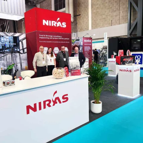 NIras team on their exhibition stand - a back wall with tower section and multiple counters