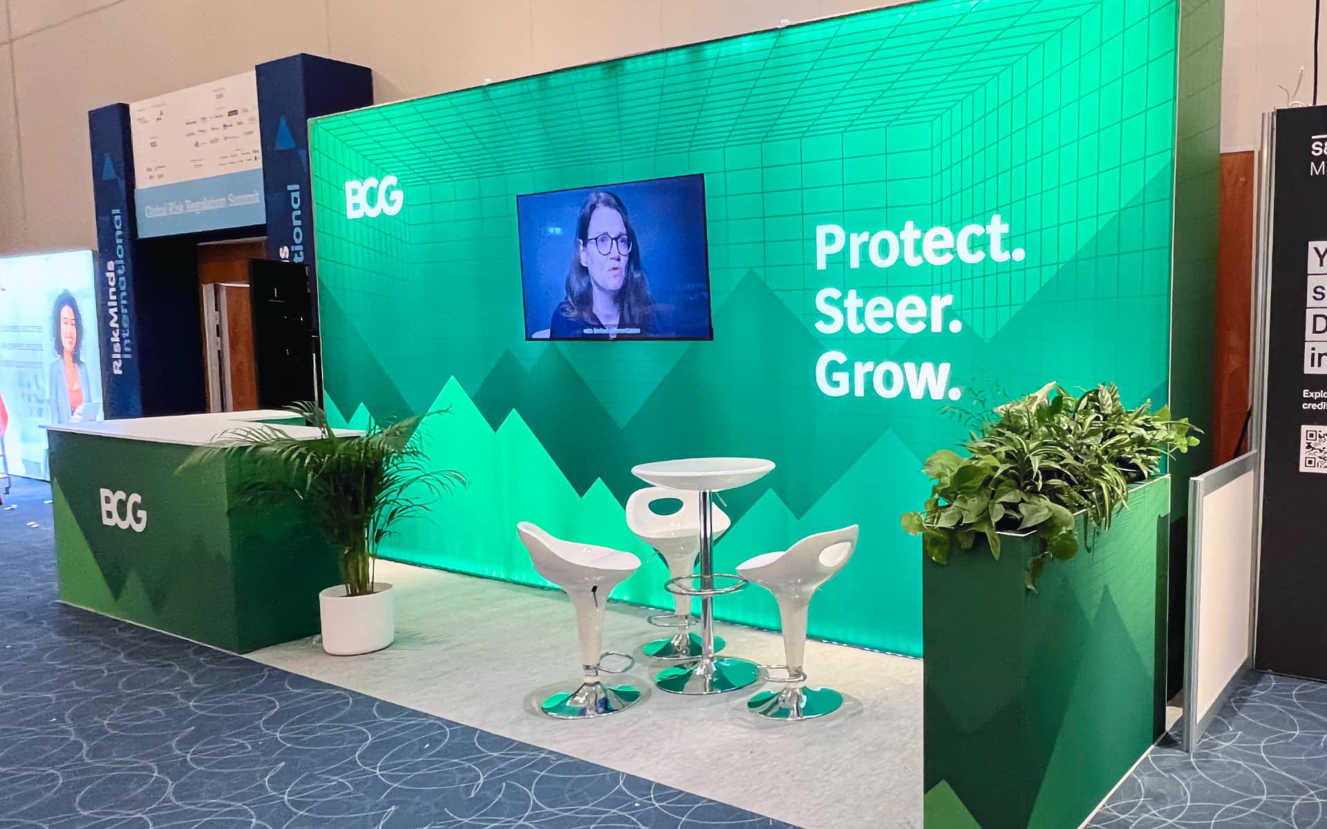 Big exhibition stand, single lightbox wall, L-shape counter and plant-topped plinth